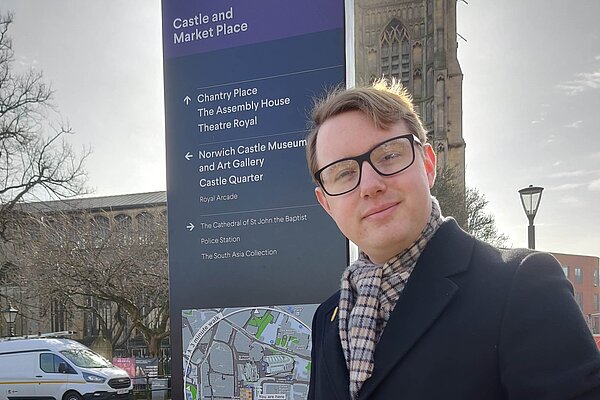 James Hawketts, Lib Dem candidate for University, in front of a tourist information display in Norwich City Centre