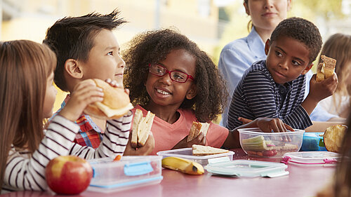 Children eating a packed lunch at a table